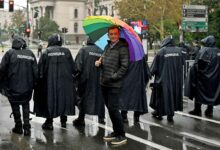 Der Belgrader Pride-Organisator Goran Miletic hält während eines Pride-Marsches am 17. September 2022 in Belgrad einen Regenbogenschirm hinter Polizisten Verbot einer Europride-Parade durch die Behörden, was Ängste vor möglichen Unruhen schürt. (Foto von Andrej ISAKOVIC / AFP)