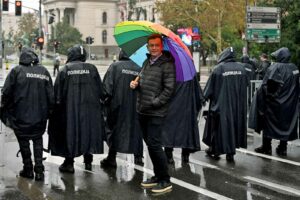 Der Belgrader Pride-Organisator Goran Miletic hält während eines Pride-Marsches am 17. September 2022 in Belgrad einen Regenbogenschirm hinter Polizisten Verbot einer Europride-Parade durch die Behörden, was Ängste vor möglichen Unruhen schürt. (Foto von Andrej ISAKOVIC / AFP)